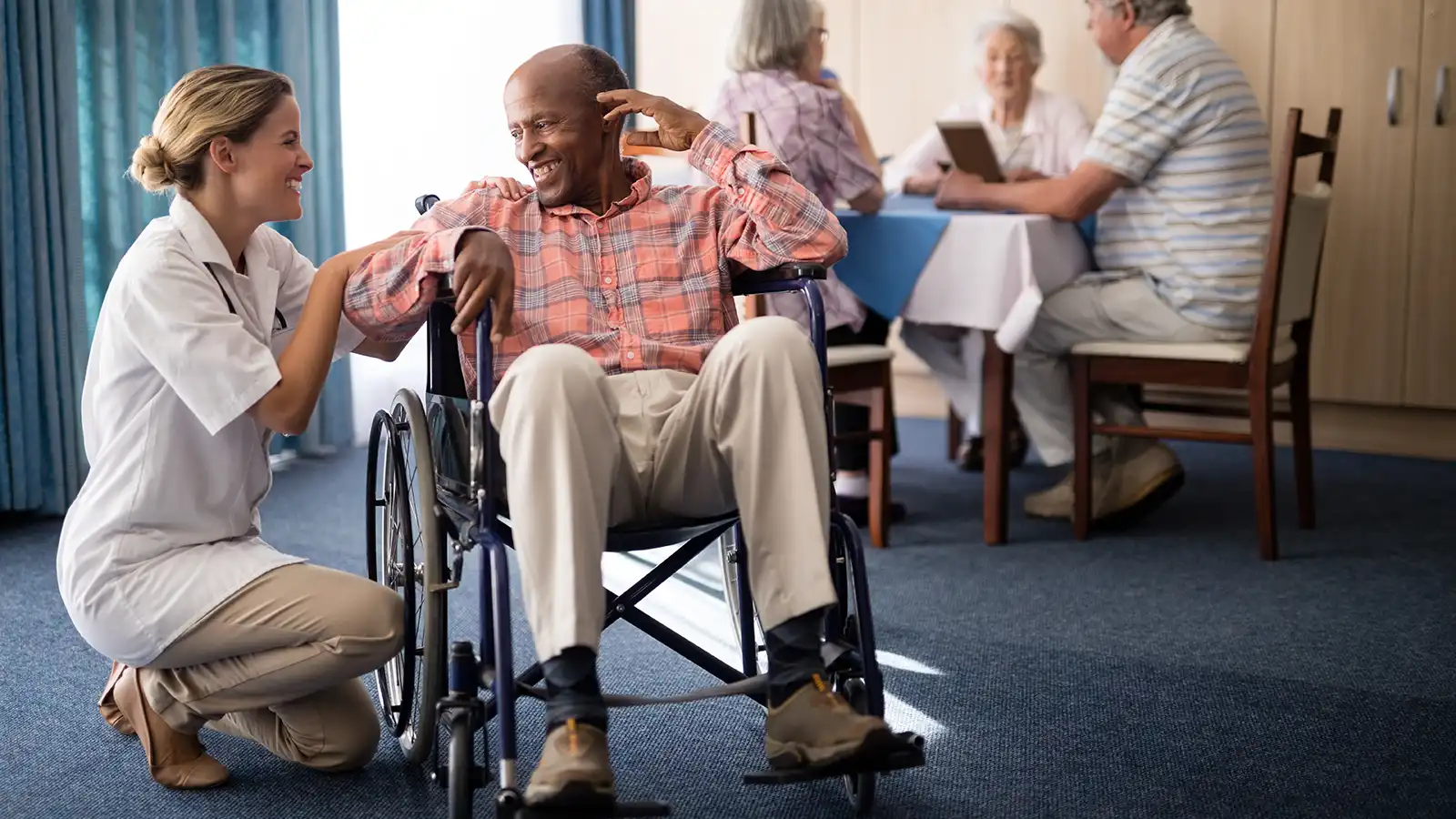Medical Staff Kneeling Next to Patient in Wheelchair